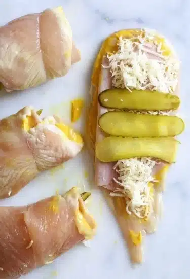 Pickle, Ham and Swiss Chicken Roll-Ups 2 Ham, Swiss, and pickle stuffed chicken roll-ups on a plate